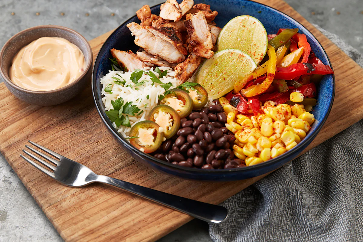 A burrito bowl with chicken, black beans, corn and sliced jalapeños